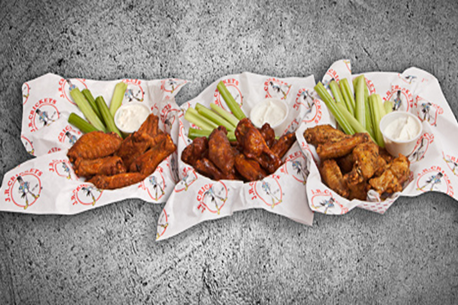 Three baskets filled with buffalo wings and celery sticks on a table