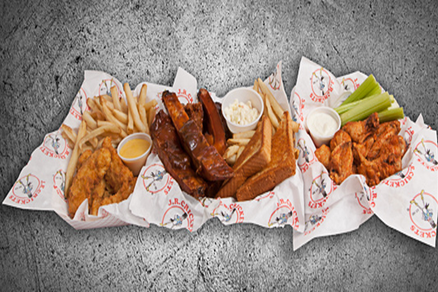 Basket filled with a variety of food items, including french fries, chicken wings, and other items