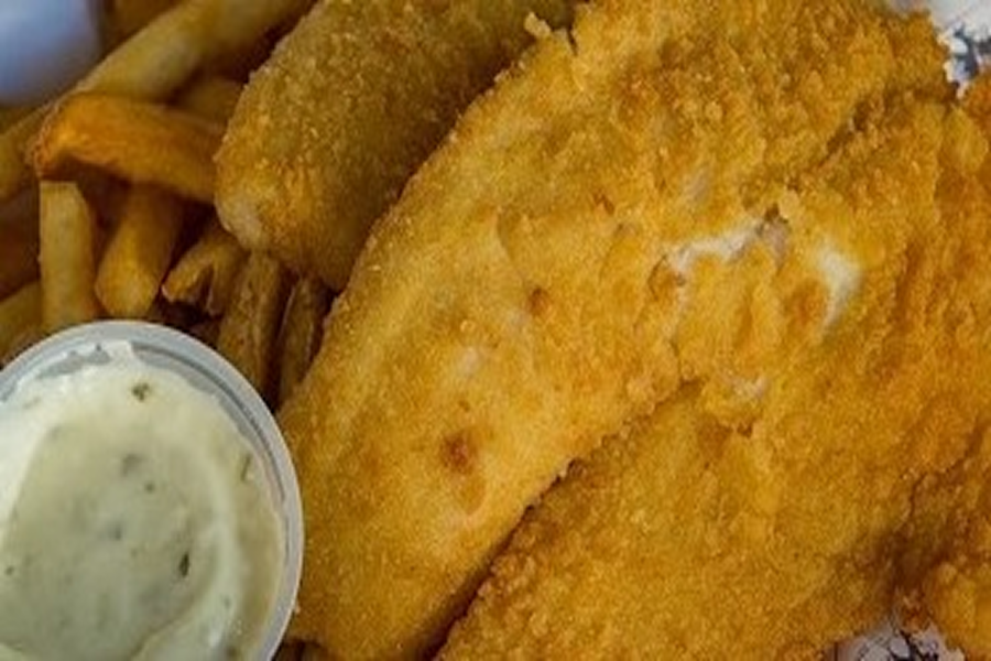 Plate of fish and chips with a side of dipping sauce, likely from a fish fry in the city