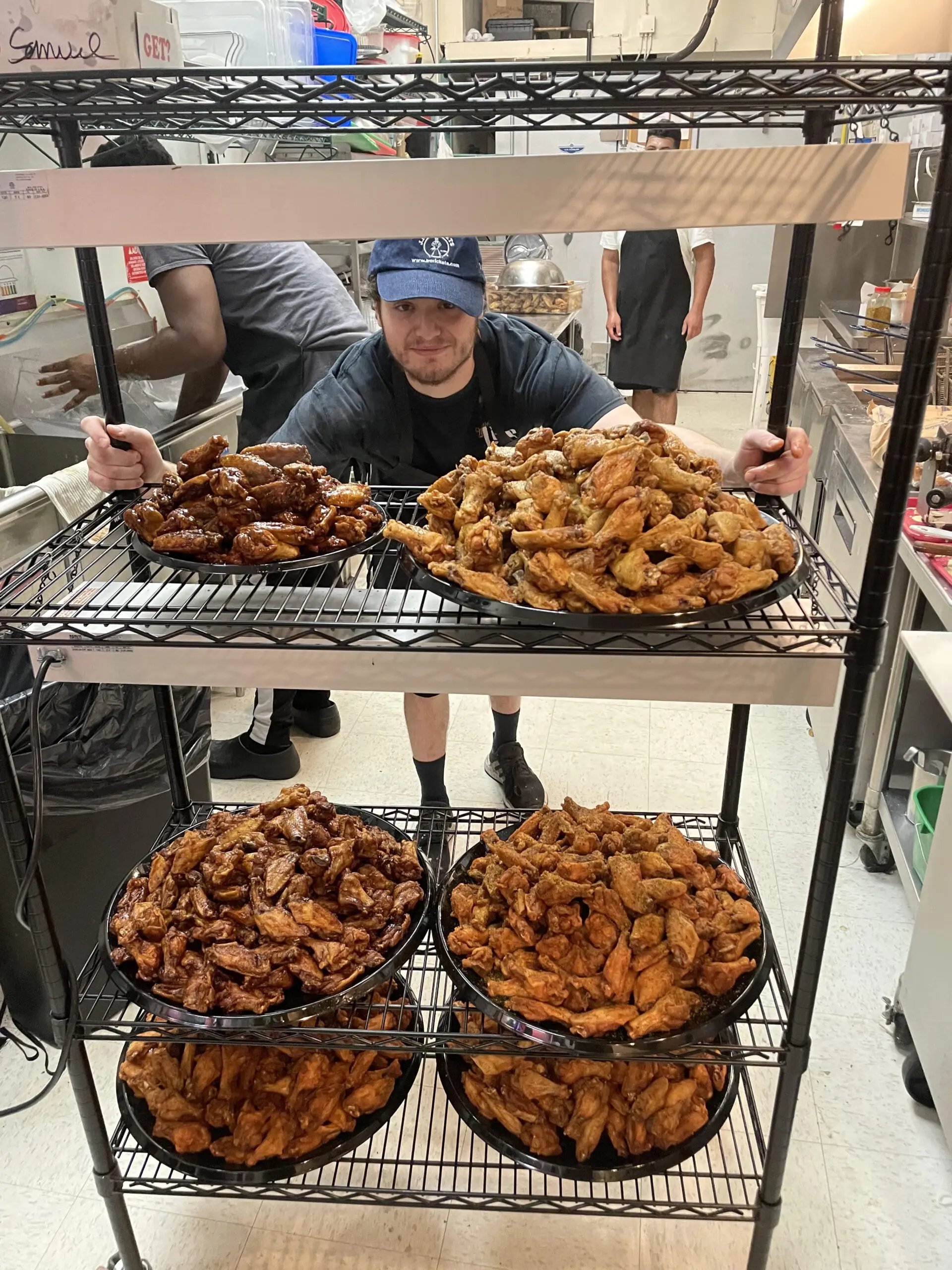 Cook behind racks of fried chicken wings