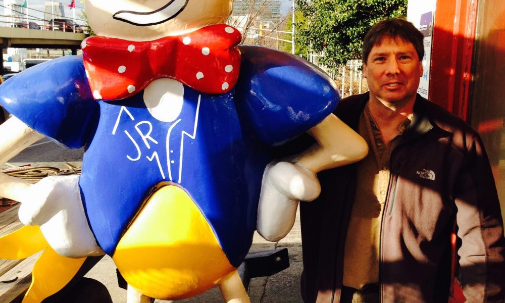 Man standing next to colorful cartoon statue